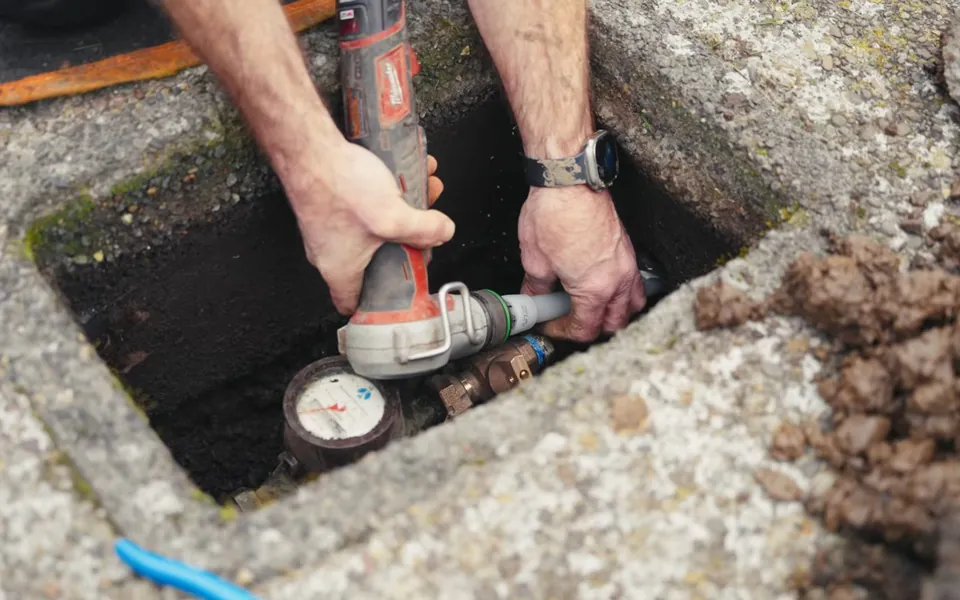 Technician checking a buried valve and pressure connection for residential plumbing service in Crown Valley, Laguna Niguel