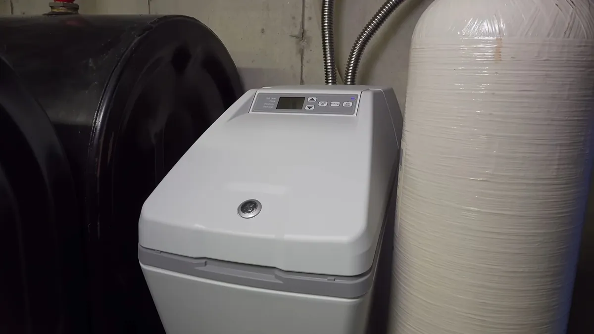Cabinet-style water softener installed beside plumbing lines for water softener vs water conditioner in Laguna Niguel