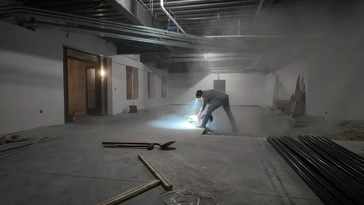 Worker finishing a commercial floor around plumbing rough-ins for residential plumbing service in Crown Valley Parkway Corridor, Laguna Niguel