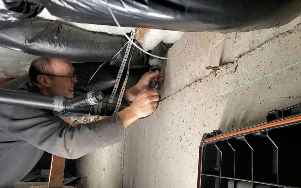 Technician measuring the slope of a crawlspace drain pipe for residential plumbing service in Hidden Hills, Laguna Niguel