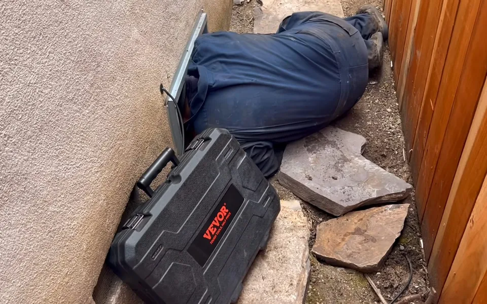 Technician entering a crawlspace with an inspection case for emergency plumbing in Laguna Niguel
