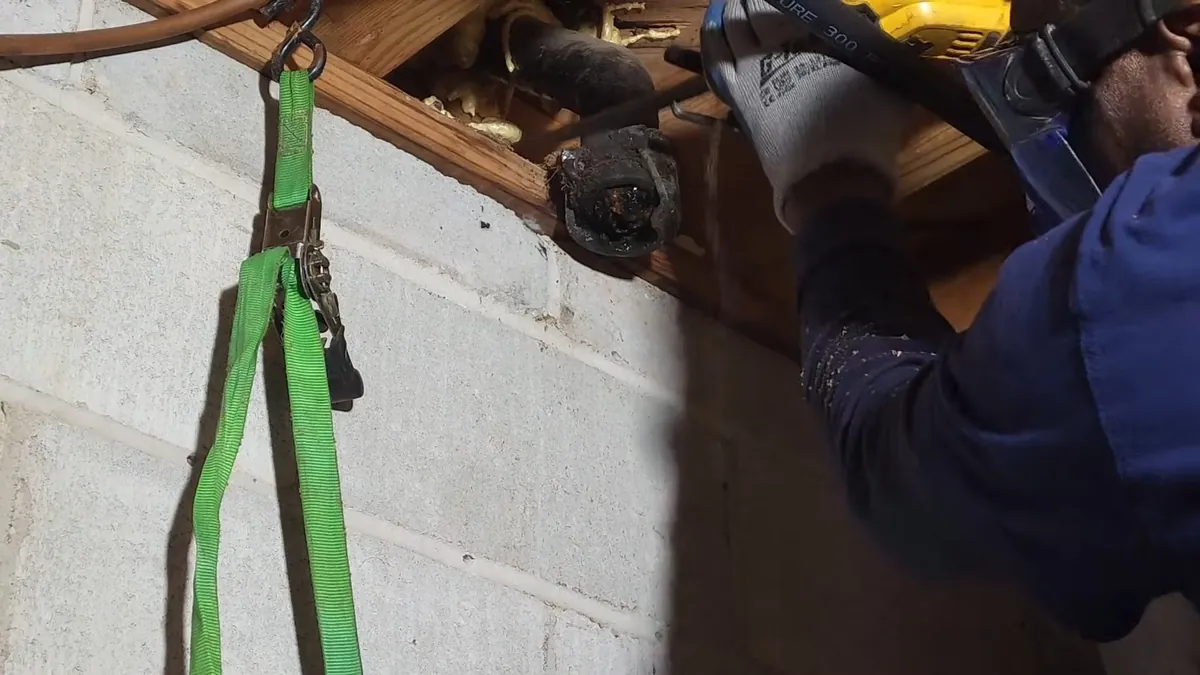 Worker cutting a cast iron drain pipe for replacement for residential plumbing service in San Clemente