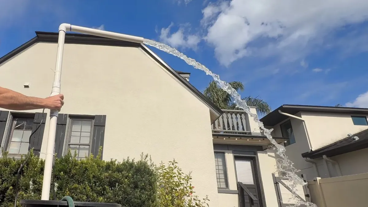 Sump pump discharge pipe rising along an exterior wall for residential plumbing service in Dana Point