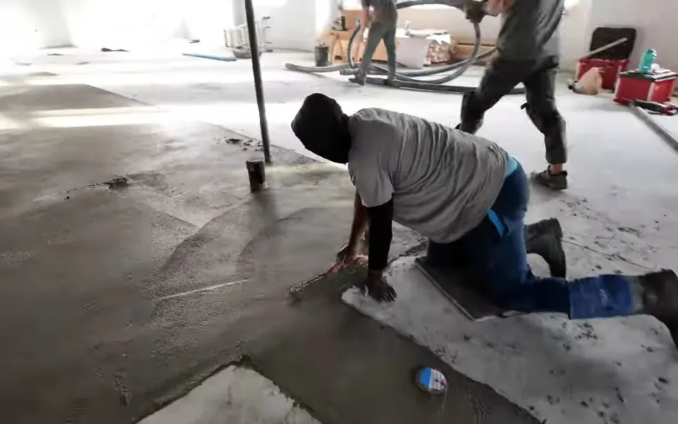 Worker smoothing the floor around a drain rough-in for residential plumbing service in South Orange County