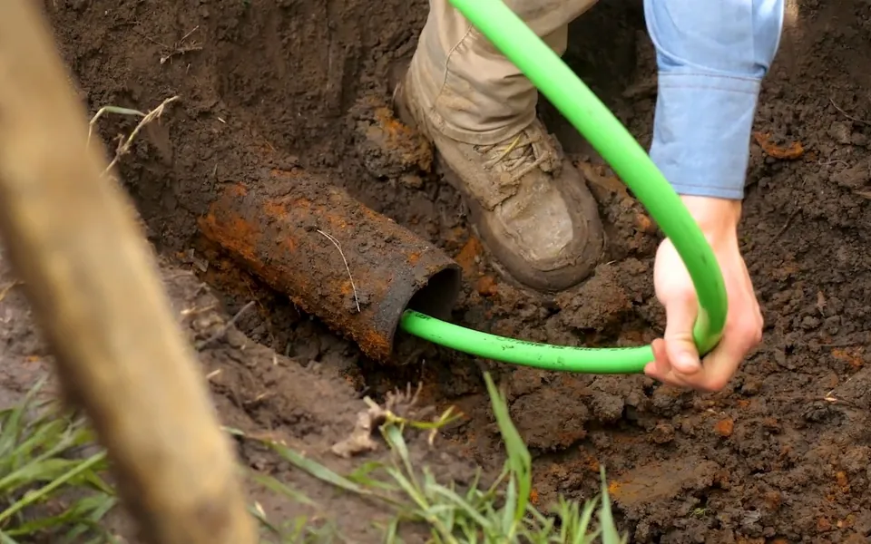 Green cured-in-place liner hose entering a sewer pipe for residential plumbing service in San Clemente