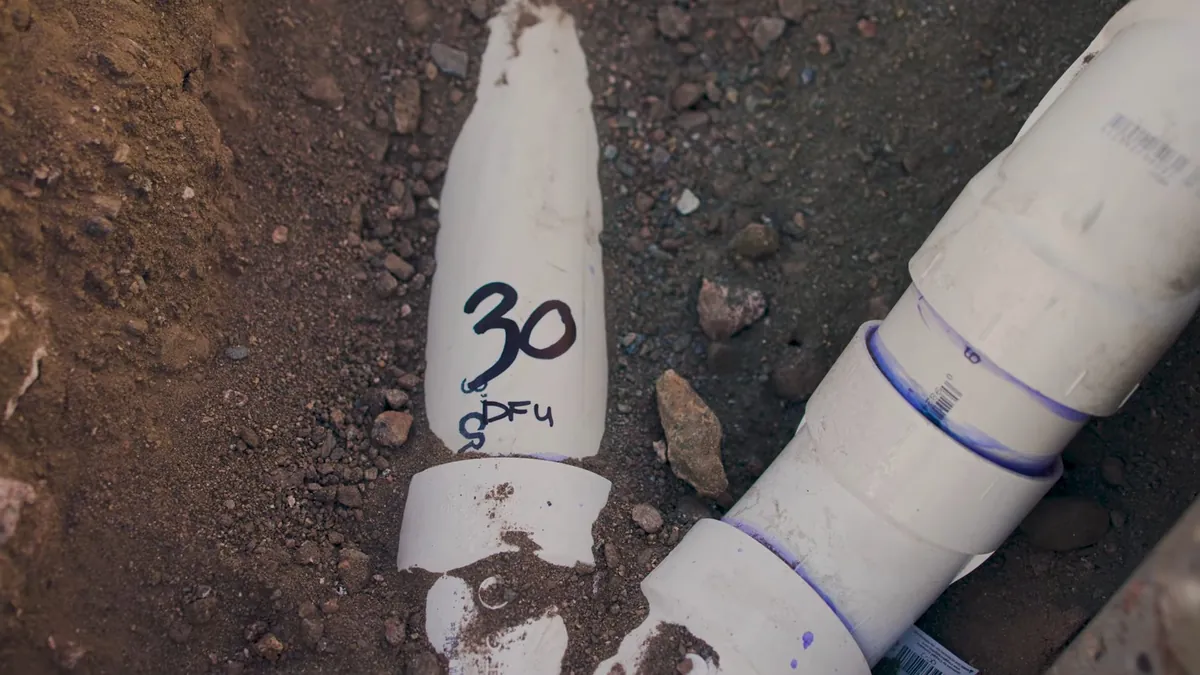 Labeled PVC branch line installed in soil for residential plumbing service in Mission Viejo