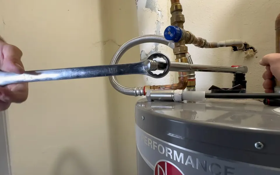 Technician loosening an anode rod from a water heater for residential plumbing service in Mission Viejo