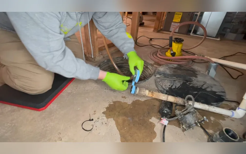 Technician repairing a pump in an opened floor basin for residential plumbing service in Coto de Caza