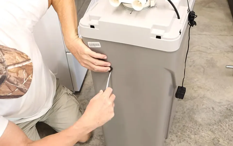 Technician opening a cabinet-style water softener for residential plumbing service in Laguna Hills