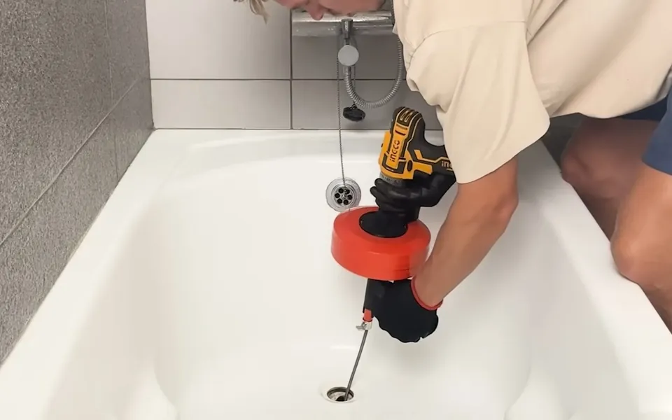Powered auger clearing a bathtub drain for shower tub repair in Laguna Niguel