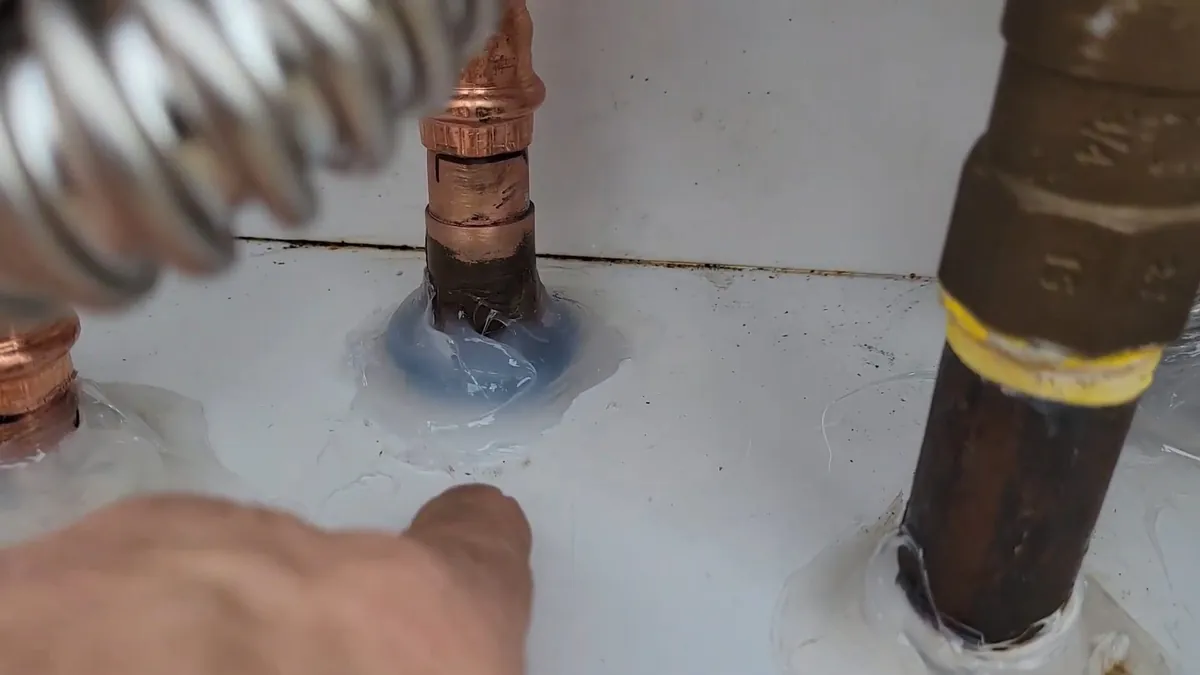 Sealed pipe penetrations beneath an outdoor tankless heater for residential plumbing service in Ladera Ranch