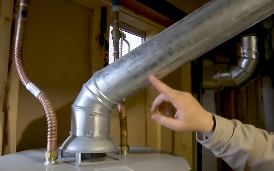 Technician inspecting a water heater flue vent for annual plumbing maintenance in Laguna Niguel