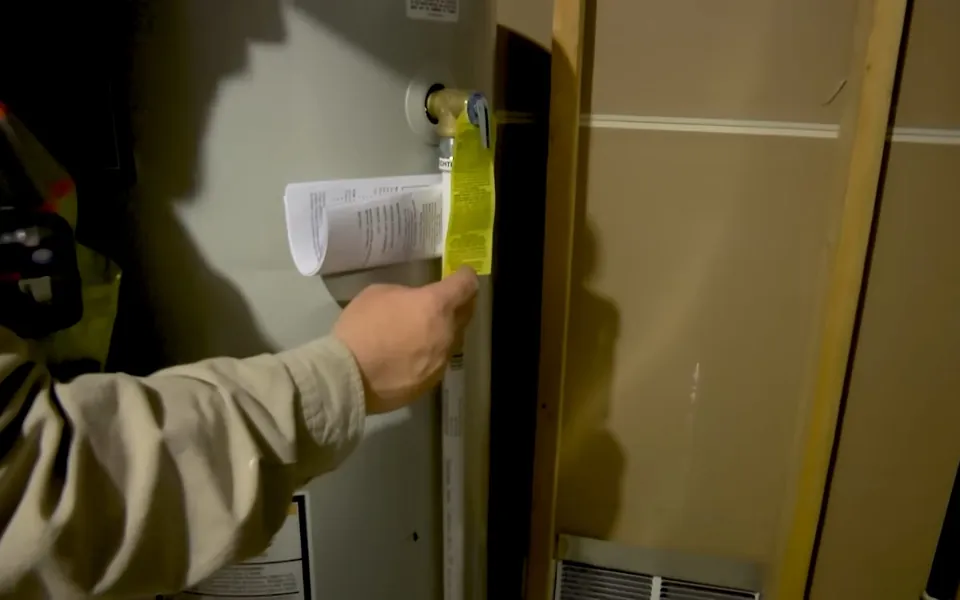 Technician reading the rating label on a water heater for preventive plumbing maintenance in Laguna Niguel